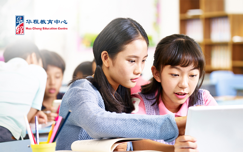 Two young chinese elementary students looking at a tablet, concentrating while working together